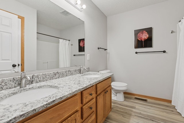 7829 Elm Grove Ln, New Hope, MN 55428 - bathroom featuring wood finished floors, double vanity, a textured ceiling, and a shower with curtain