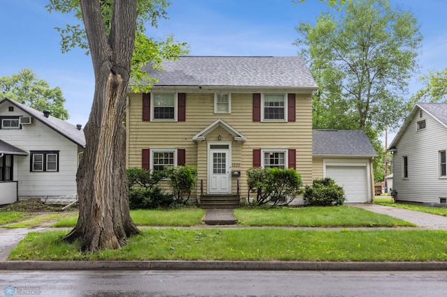 1330 12th St N, Fargo, ND 58102 - colonial house featuring an attached garage, driveway, a front lawn, entry steps, and a shingled roof