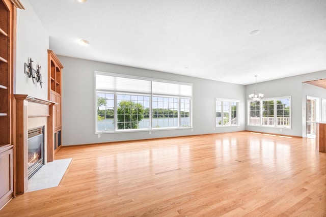1215 Shore Dr SW, Hutchinson, MN 55350 - unfurnished living room with a chandelier, a fireplace, light wood-style floors, and built in features