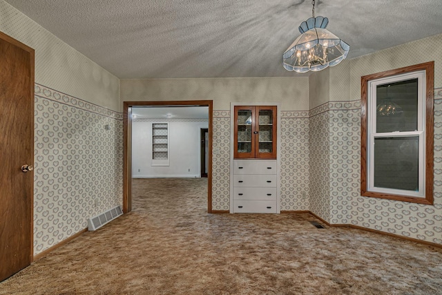 906 Holcombe Ave, Litchfield, MN 55355 - carpeted spare room featuring wallpapered walls, a chandelier, and a textured ceiling