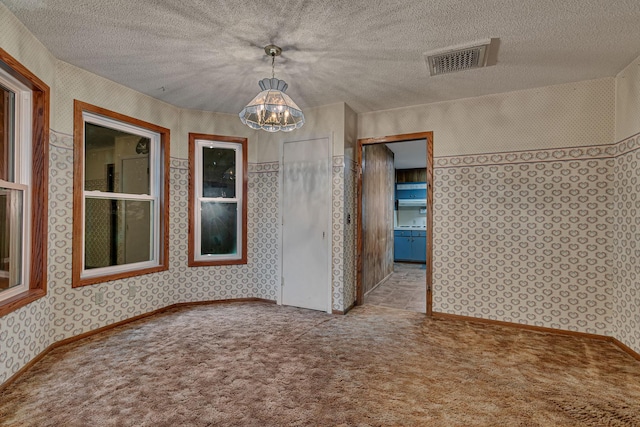 906 Holcombe Ave, Litchfield, MN 55355 - empty room featuring wallpapered walls, a chandelier, carpet flooring, and a textured ceiling