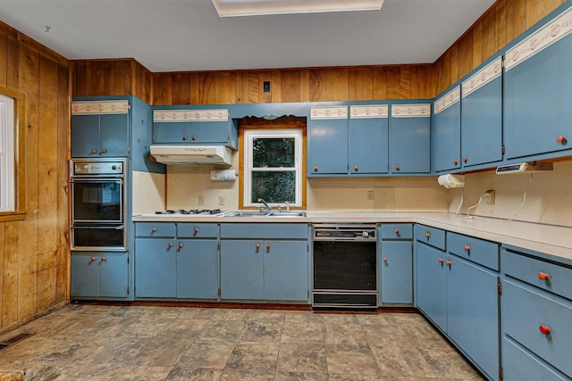906 Holcombe Ave, Litchfield, MN 55355 - kitchen featuring black appliances, a warming drawer, under cabinet range hood, blue cabinetry, and wooden walls