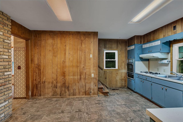 906 Holcombe Ave, Litchfield, MN 55355 - kitchen featuring blue cabinets, wood walls, a warming drawer, black oven, and light countertops