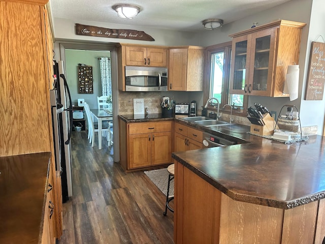 515 2nd St SW, New Richland, MN 56072 - kitchen featuring appliances with stainless steel finishes, a peninsula, dark wood-style flooring, glass insert cabinets, and dark countertops