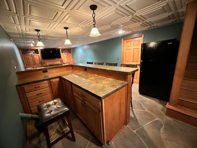 515 2nd St SW, New Richland, MN 56072 - kitchen featuring freestanding refrigerator, an ornate ceiling, a breakfast bar area, brown cabinetry, and a peninsula