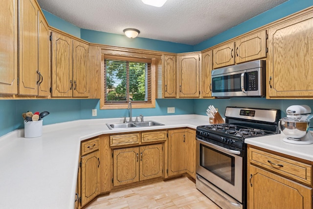 7140 Ivy Ridge Ct, Lino Lakes, MN 55014 - kitchen with stainless steel appliances, light countertops, a textured ceiling, and light wood-style floors