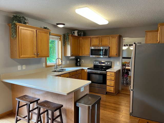 100 Barkley Cir W, Cannon Falls, MN 55009 - kitchen featuring stainless steel appliances, a peninsula, light countertops, light wood finished floors, and a breakfast bar area