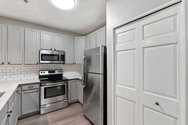 645 1st St Unit 305, Minneapolis, MN 55401 - kitchen with appliances with stainless steel finishes, decorative backsplash, light wood-type flooring, light countertops, and gray cabinetry