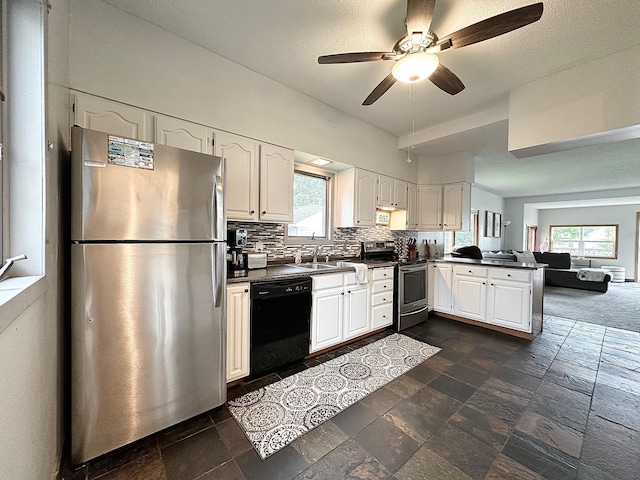511 3rd St, Nashwauk, MN 55769 - kitchen with appliances with stainless steel finishes, dark countertops, a peninsula, ceiling fan, and stone tile flooring