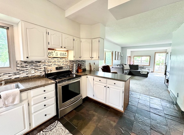 511 3rd St, Nashwauk, MN 55769 - kitchen featuring stainless steel range with electric cooktop, dark countertops, stone tile floors, backsplash, and a textured ceiling