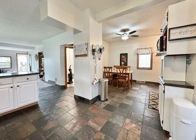 511 3rd St, Nashwauk, MN 55769 - kitchen with stone tile floors, healthy amount of natural light, white cabinetry, dark countertops, and a textured ceiling