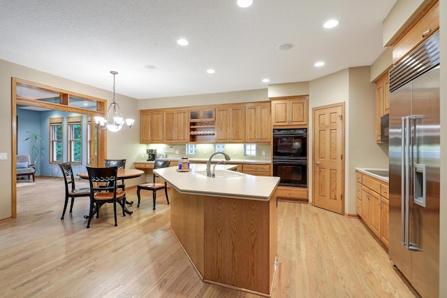 7569 Blackoaks Ln N, Maple Grove, MN 55311 - kitchen featuring stainless steel built in refrigerator, a kitchen island with sink, light countertops, open shelves, and light wood-style floors