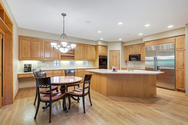 7569 Blackoaks Ln N, Maple Grove, MN 55311 - kitchen with black appliances, light countertops, light wood-style floors, a kitchen island with sink, and a chandelier