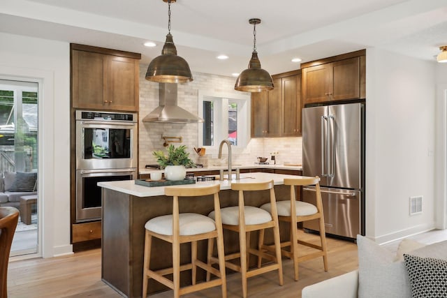 3520 27th Ave S, Minneapolis, MN 55406 - kitchen with stainless steel appliances, wall chimney range hood, backsplash, light wood-style flooring, and light countertops