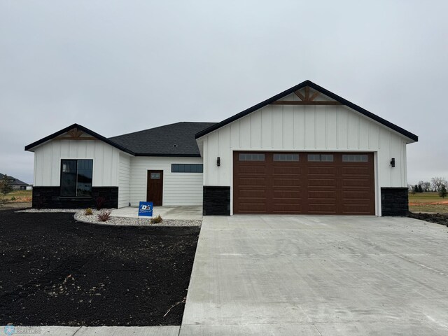 215 Emma Ct, Mapleton, ND 58059 - modern farmhouse with board and batten siding, stone siding, concrete driveway, a shingled roof, and an attached garage