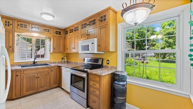 918 Trott Ave SW, Willmar, MN 56201 - kitchen featuring white appliances, brown cabinetry, glass insert cabinets, light tile patterned floors, and light countertops