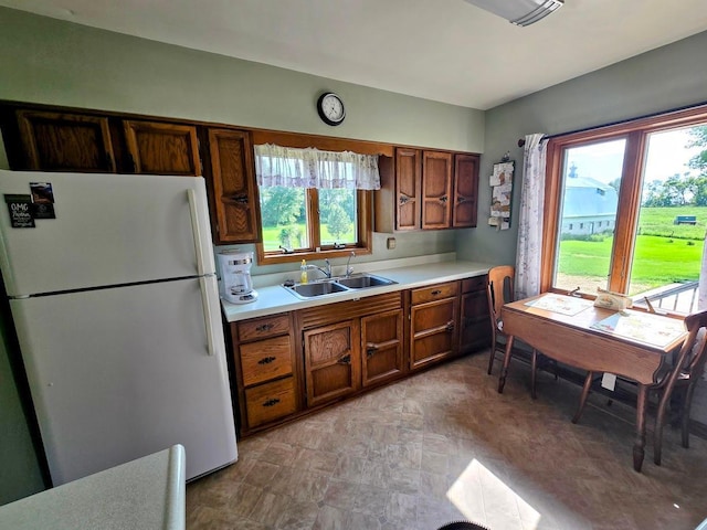 2047 60th Ave, Altona Twp, MN 56164 - kitchen with freestanding refrigerator, healthy amount of natural light, light countertops, and brown cabinetry