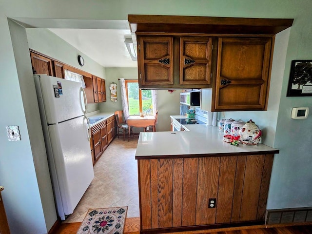 2047 60th Ave, Altona Twp, MN 56164 - kitchen featuring freestanding refrigerator, a peninsula, light countertops, and brown cabinetry