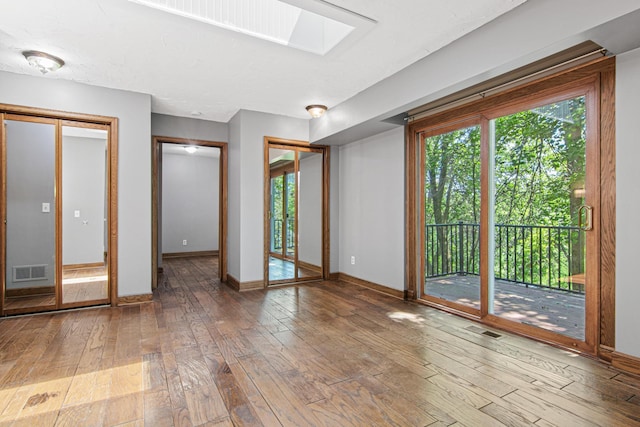 6230 Elm Ridge Cir, Corcoran, MN 55340 - unfurnished bedroom with access to exterior, hardwood / wood-style flooring, multiple windows, and a skylight