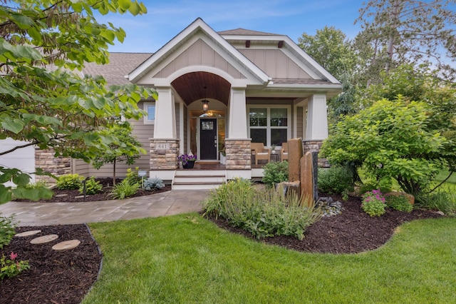 641 Callahan Pl, Mendota Heights, MN 55118 - craftsman house featuring board and batten siding, stone siding, a front yard, a porch, and roof with shingles