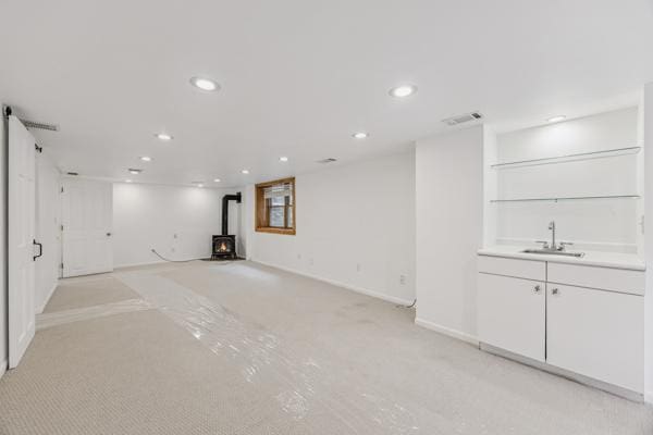 3916 Thomas Ave S, Minneapolis, MN 55410 - unfurnished living room with a wood stove, light carpet, recessed lighting, and bar with sink