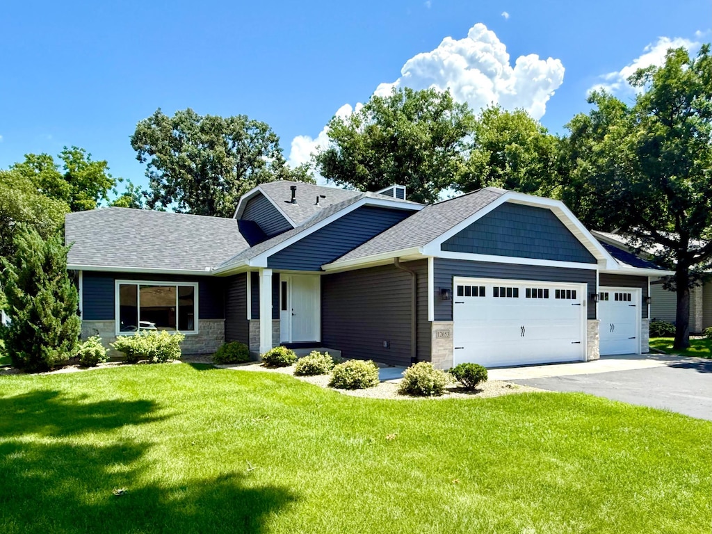 12653 Hastings St NE, Blaine, MN 55449 - view of front of house with stone siding, a garage, driveway, and roof with shingles