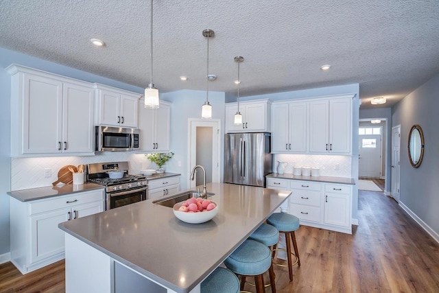 1251 149th St W, Rosemount, MN 55068 - kitchen with appliances with stainless steel finishes, an island with sink, decorative backsplash, dark wood-type flooring, and white cabinets