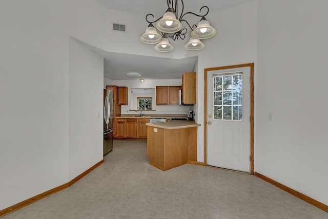 4384 Clearwater Rd, Saint Cloud, MN 56301 - kitchen with appliances with stainless steel finishes, brown cabinetry, a chandelier, light countertops, and a peninsula