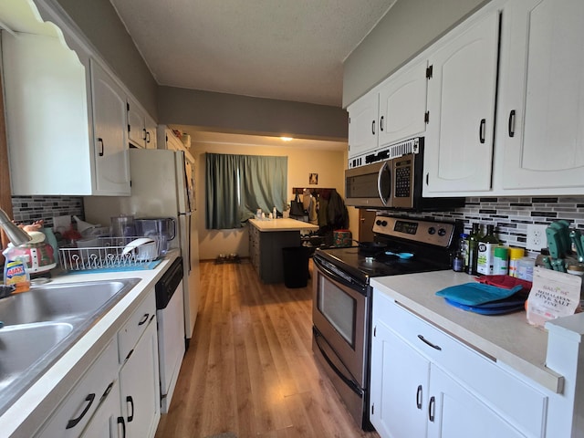 108 9th St, Morris, MN 56267 - kitchen with appliances with stainless steel finishes, white cabinets, tasteful backsplash, and light wood finished floors