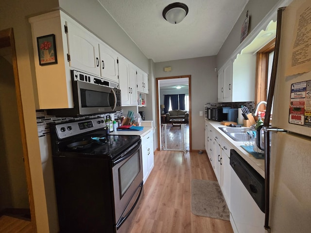 108 9th St, Morris, MN 56267 - kitchen with stainless steel appliances, backsplash, white cabinetry, light wood-style flooring, and light countertops