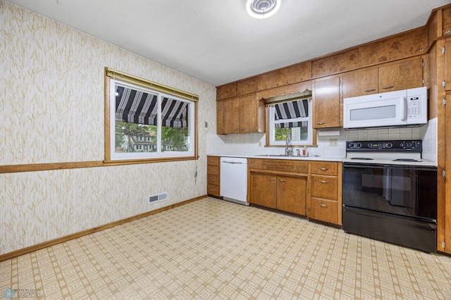1109 14th St N, Moorhead, MN 56560 - kitchen with white appliances, wallpapered walls, light flooring, light countertops, and brown cabinets