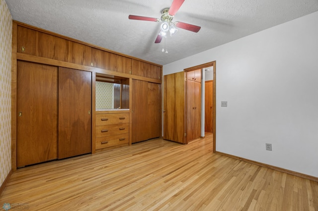 1109 14th St N, Moorhead, MN 56560 - unfurnished bedroom with light wood finished floors, a textured ceiling, two closets, and a ceiling fan
