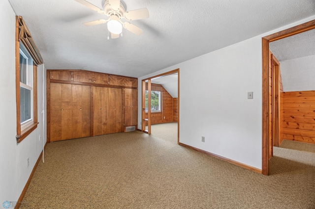1109 14th St N, Moorhead, MN 56560 - unfurnished bedroom with lofted ceiling, light carpet, a closet, wood walls, and a textured ceiling