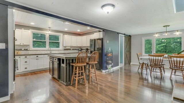 14645 Chapel Rd, Edgewater, WI 54817 - kitchen with fridge with ice dispenser, a barn door, backsplash, wood finished floors, and white cabinetry