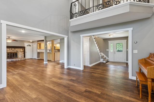 27088 130th St, Staples, MN 56479 - unfurnished living room with stairway, wood finished floors, ceiling fan, a towering ceiling, and a brick fireplace