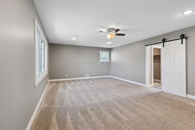 27088 130th St, Staples, MN 56479 - unfurnished bedroom with light carpet, a barn door, recessed lighting, a walk in closet, and ceiling fan