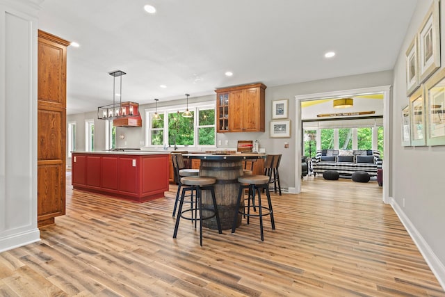 N5887 1110th St, Oak Grove Twp, WI 54021 - kitchen featuring a center island, light wood-style floors, recessed lighting, glass insert cabinets, and a kitchen bar