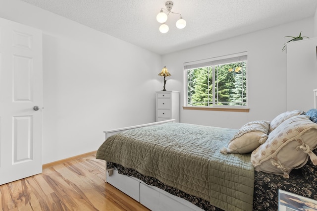 14939 Pinto Ln, Savage, MN 55378 - bedroom featuring light wood-type flooring, a textured ceiling, and a chandelier