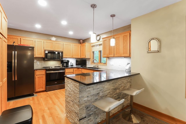 2583 Lost Lake Rd, Mound, MN 55364 - kitchen with appliances with stainless steel finishes, light wood finished floors, a peninsula, a breakfast bar area, and tasteful backsplash
