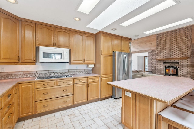 3718 Big Mcgraw Rd, Blaine Twp, WI 54830 - kitchen with white microwave, freestanding refrigerator, black electric stovetop, a fireplace, and brick patterned flooring