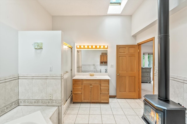 3718 Big Mcgraw Rd, Blaine Twp, WI 54830 - full bath featuring a wood stove, tile patterned flooring, vanity, a garden tub, and a stall shower