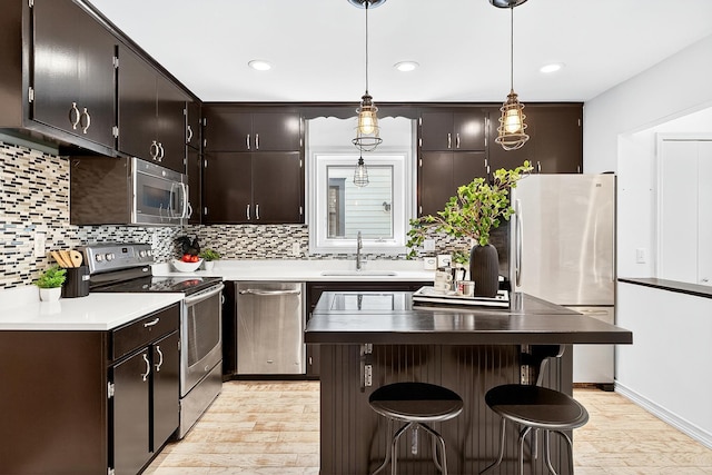 4716 30th Ave S, Minneapolis, MN 55406 - kitchen with appliances with stainless steel finishes, light wood finished floors, backsplash, a breakfast bar, and a kitchen island