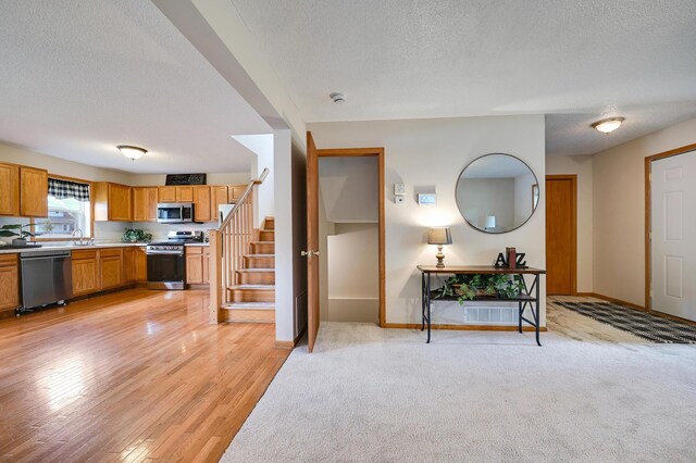 927 Charles Ave, Saint Paul, MN 55104 - kitchen featuring stainless steel appliances, a textured ceiling, light countertops, light wood finished floors, and brown cabinets