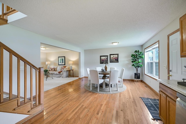 927 Charles Ave, Saint Paul, MN 55104 - dining space featuring stairway, light wood-style floors, and a textured ceiling
