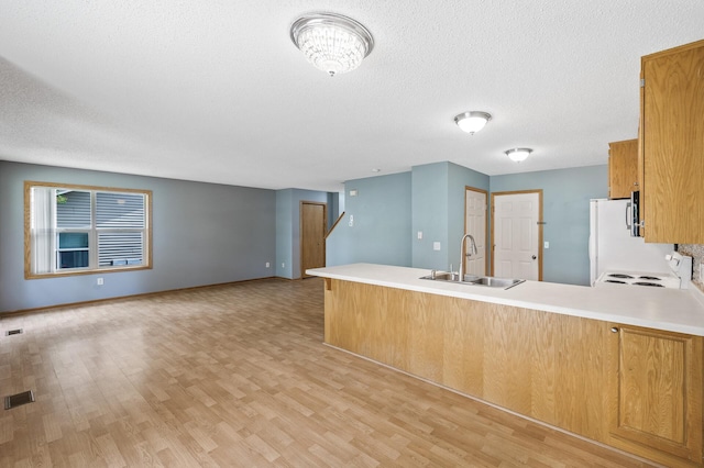 1011 6th Ave NE, Buffalo, MN 55313 - kitchen featuring a peninsula, light wood finished floors, brown cabinets, open floor plan, and a textured ceiling