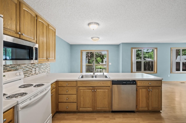1011 6th Ave NE, Buffalo, MN 55313 - kitchen with stainless steel appliances, light wood-style floors, a peninsula, light countertops, and a textured ceiling