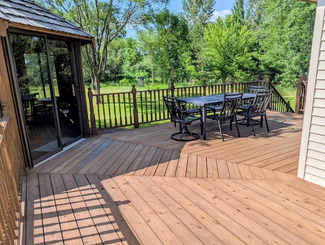 1541 282nd Ln NW, Isanti Twp, MN 55040 - wooden deck with outdoor dining area, view of wooded area, and a yard