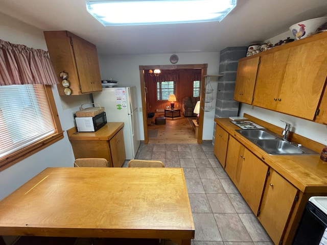 31519 243rd Ave, Moose Creek Twp, MN 56676 - kitchen with black microwave, range, freestanding refrigerator, light tile patterned floors, and brown cabinetry