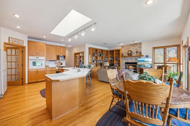 1181 12th Ave NW, New Brighton, MN 55112 - dining space featuring a brick fireplace, a skylight, light wood-style floors, and recessed lighting