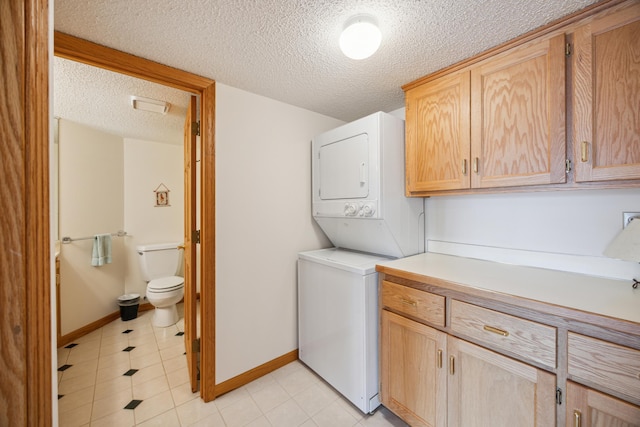 1181 12th Ave NW, New Brighton, MN 55112 - laundry area featuring estacked washer and dryer, a textured ceiling, cabinet space, and light tile patterned floors